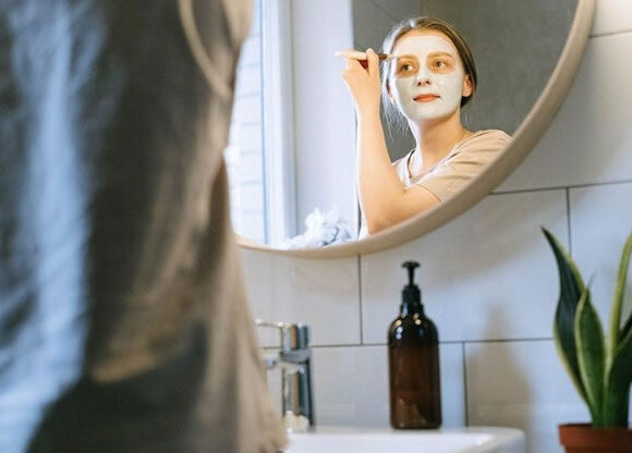 Young woman at home applying naturally made anti fungal paste to face