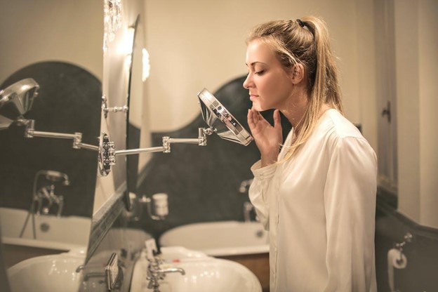 female_looking_in_mirror_dealing_with_itchy_acne